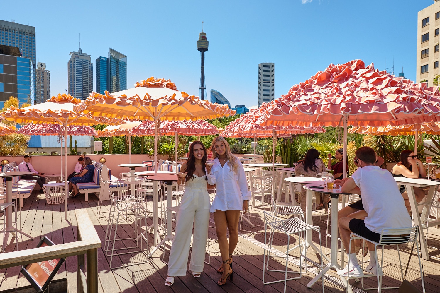 Photo showing View of bar and city skyline from Slims Rooftop Bar with 2 patrons posing